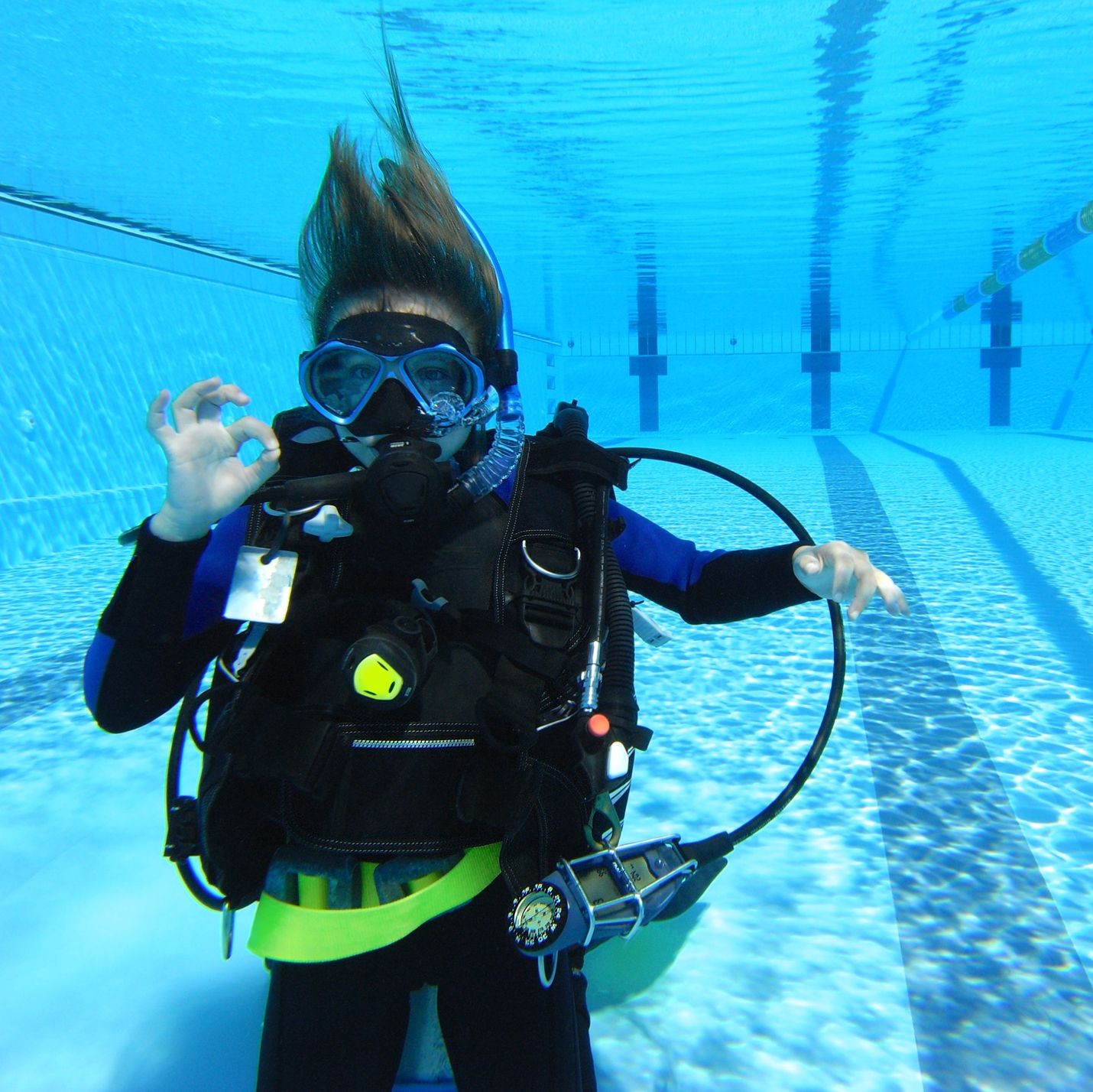 Young scuba diver in a swimming pool signaling OK